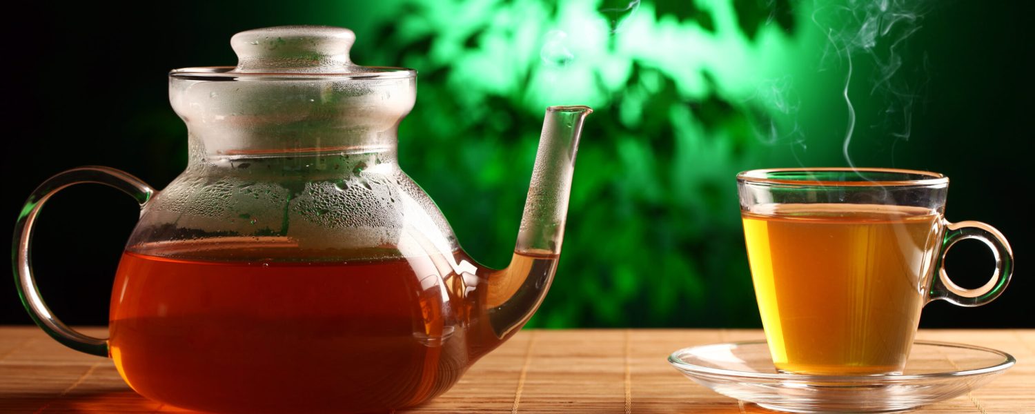Hot green tea in glass teapot and cup